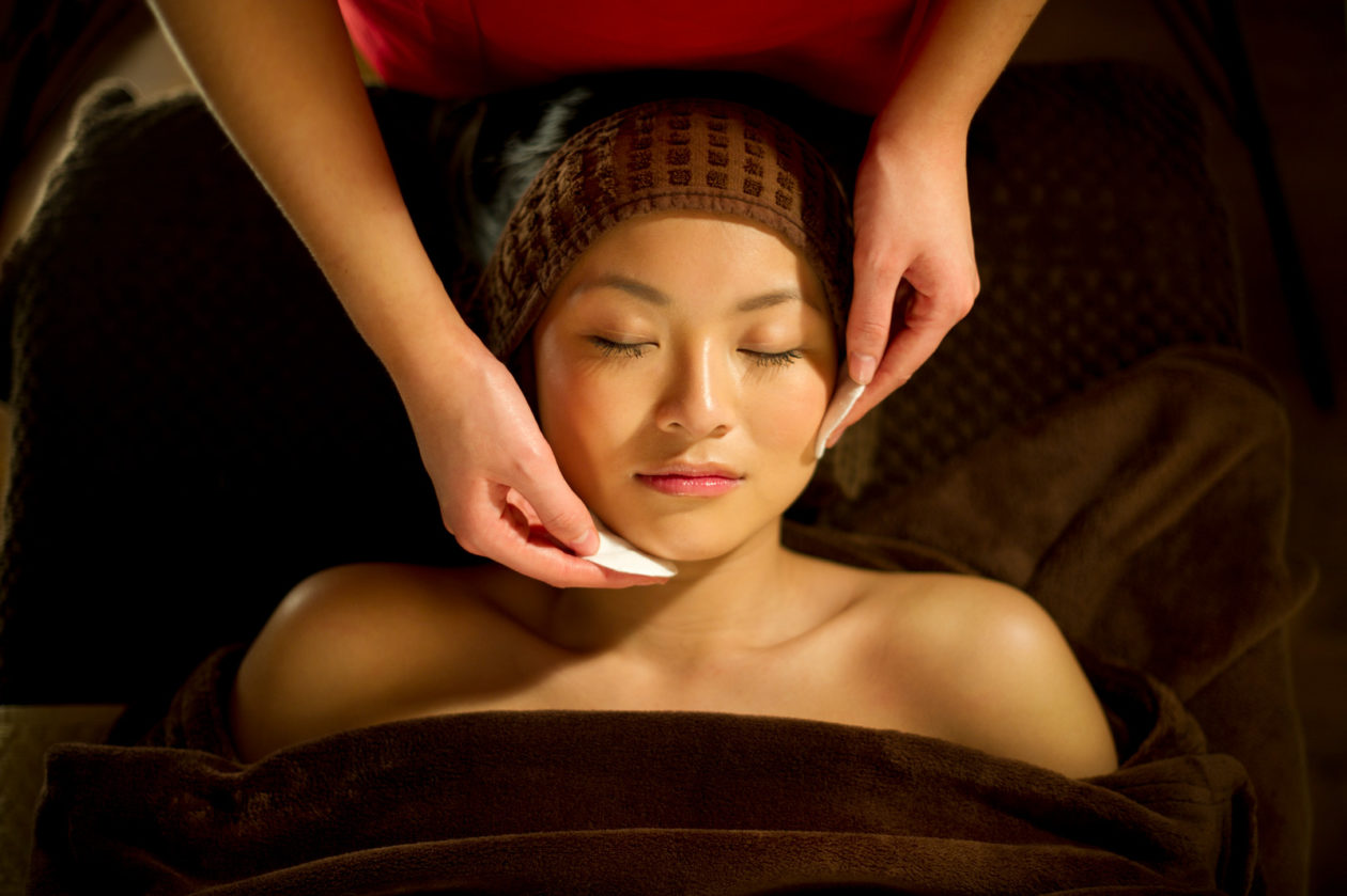 young woman gets facial in spa
