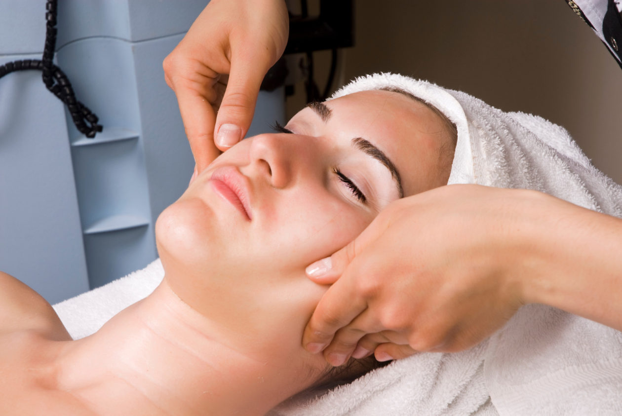 Young woman having facial massage in beauty spa