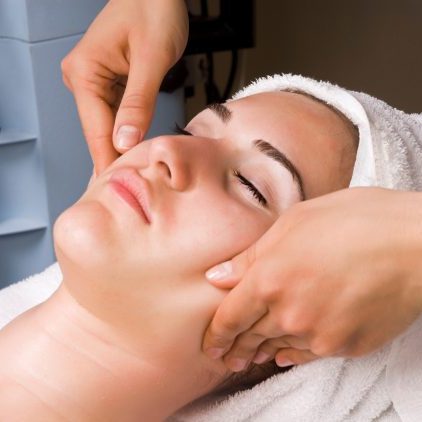 Young woman having facial massage in beauty spa